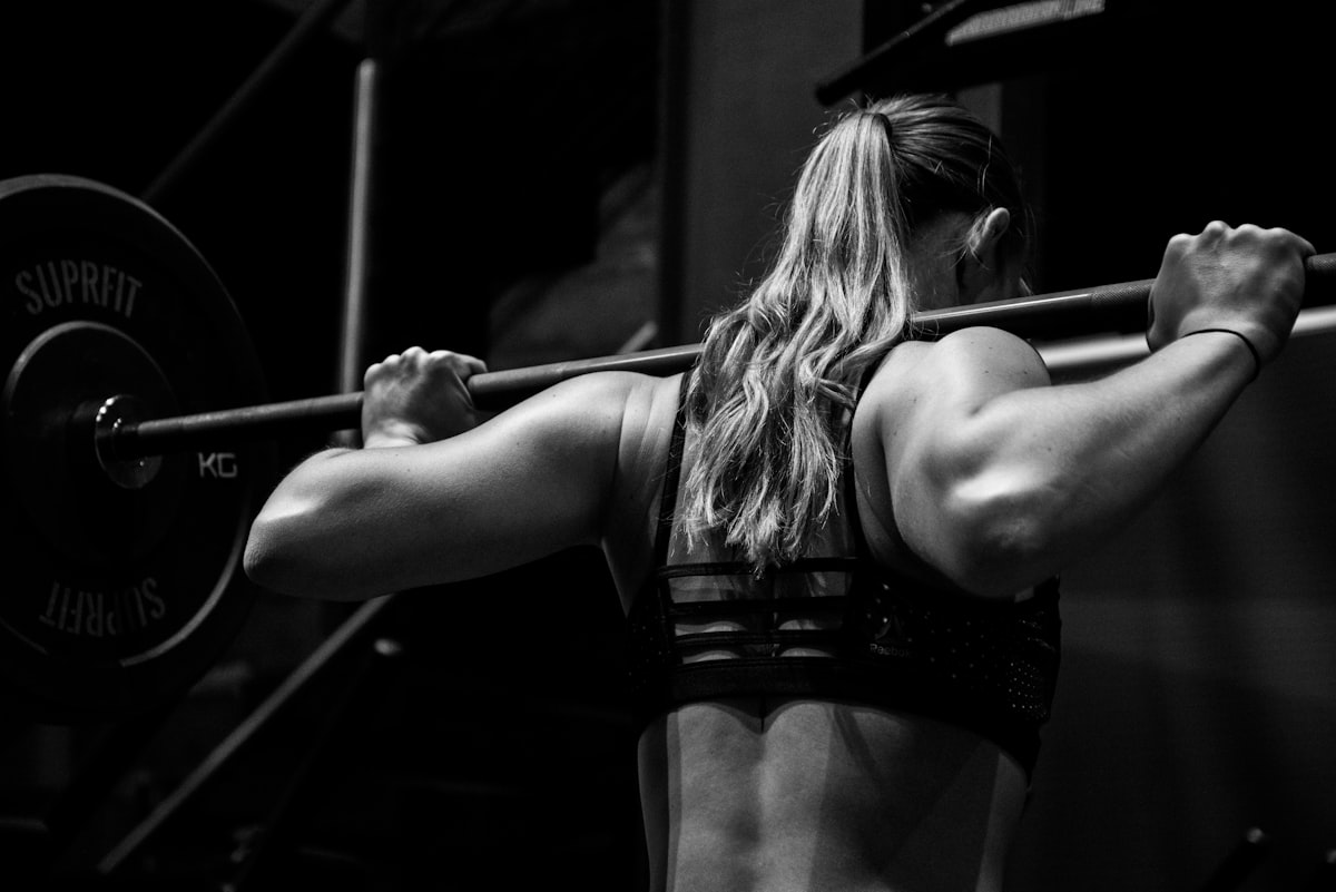 Athlete preparing to back squat a barbell in a dark gym